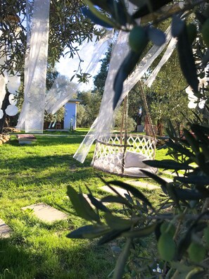 A garden with a swing chair and a white fence.