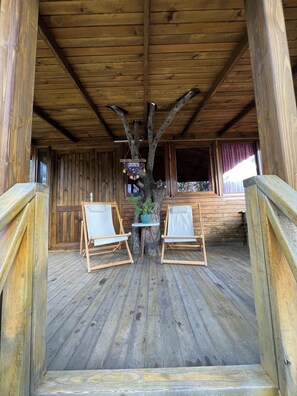 A wooden cabin with a rustic interior, featuring two wooden chairs and a small table with a hanging decoration. - Yiva Kazdaglari (Edremit)