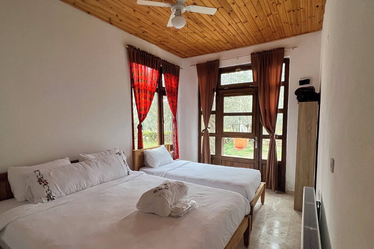 A bedroom with two beds, wooden ceiling, a ceiling fan, and a radiator.