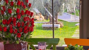 A table set with various dishes, a bouquet of red roses, and a view of a garden. - Yiva Kazdaglari (Edremit)