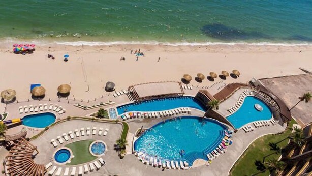 A resort with multiple swimming pools, sun loungers, and beach umbrellas.