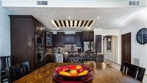 A modern kitchen with dark wood cabinets, stainless steel appliances, and a dining area with a wooden table and chairs.