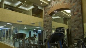 A gym with exercise equipment, a stone wall, and a glass wall reflecting the interior.