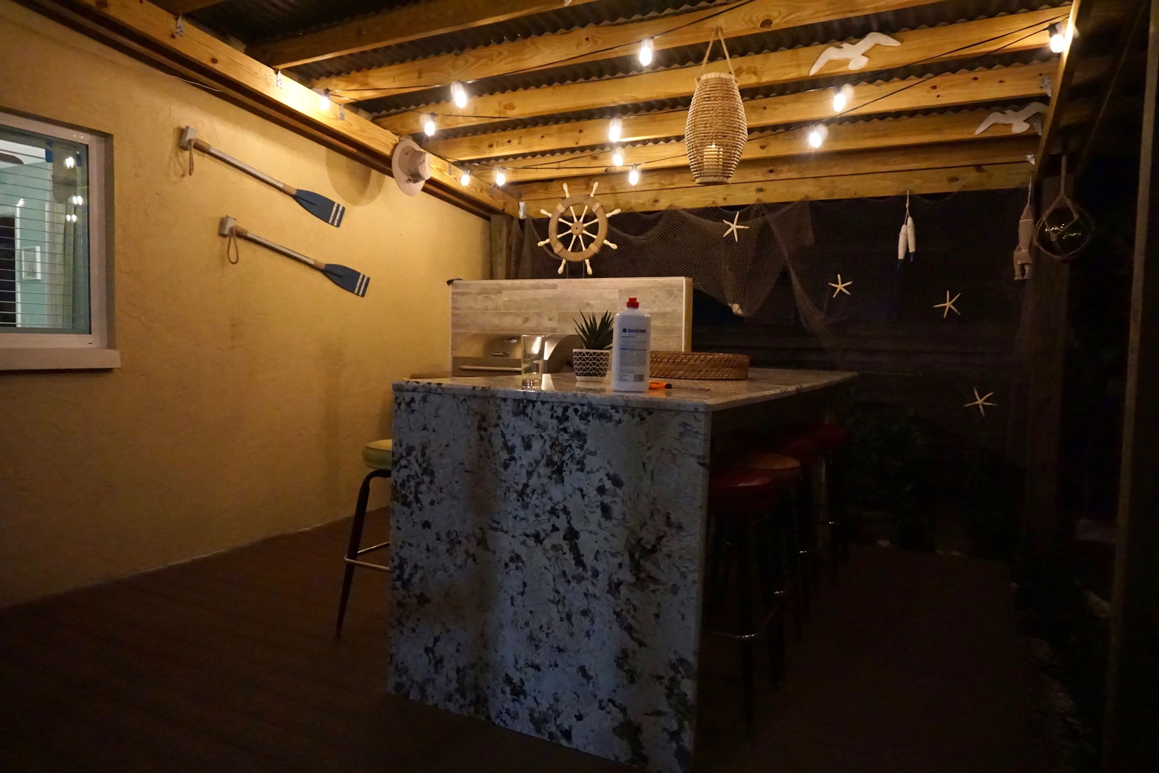 A cozy bar area with a wooden ceiling, string lights, and nautical decorations.