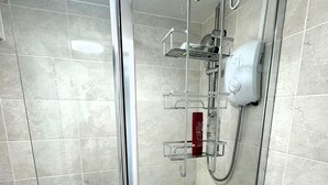 Un baño moderno con cabina de ducha de vidrio, inodoro y secamanos.