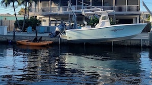 Una casa con balcón, un barco amarrado al frente y una palmera.