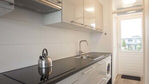 A modern kitchen with a kettle, sink, and built-in oven. - Blue Shell With Private Parking Garage (Zandvoort)