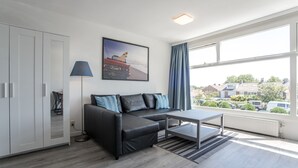 A modern living room with a sofa, a coffee table, and a painting on the wall. - Blue Shell With Private Parking Garage (Zandvoort)
