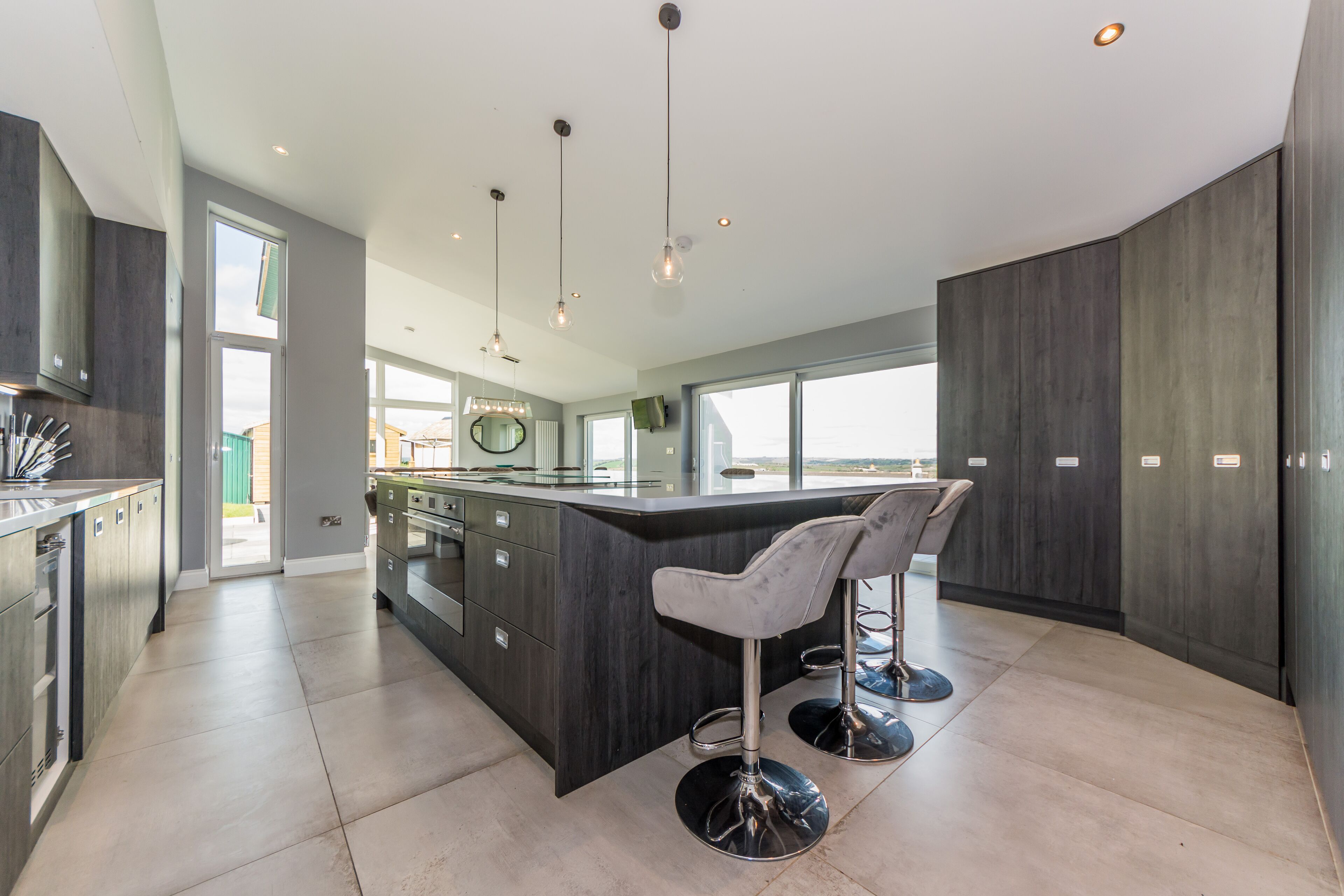 A modern kitchen with dark cabinetry, a central island, and bar stools.