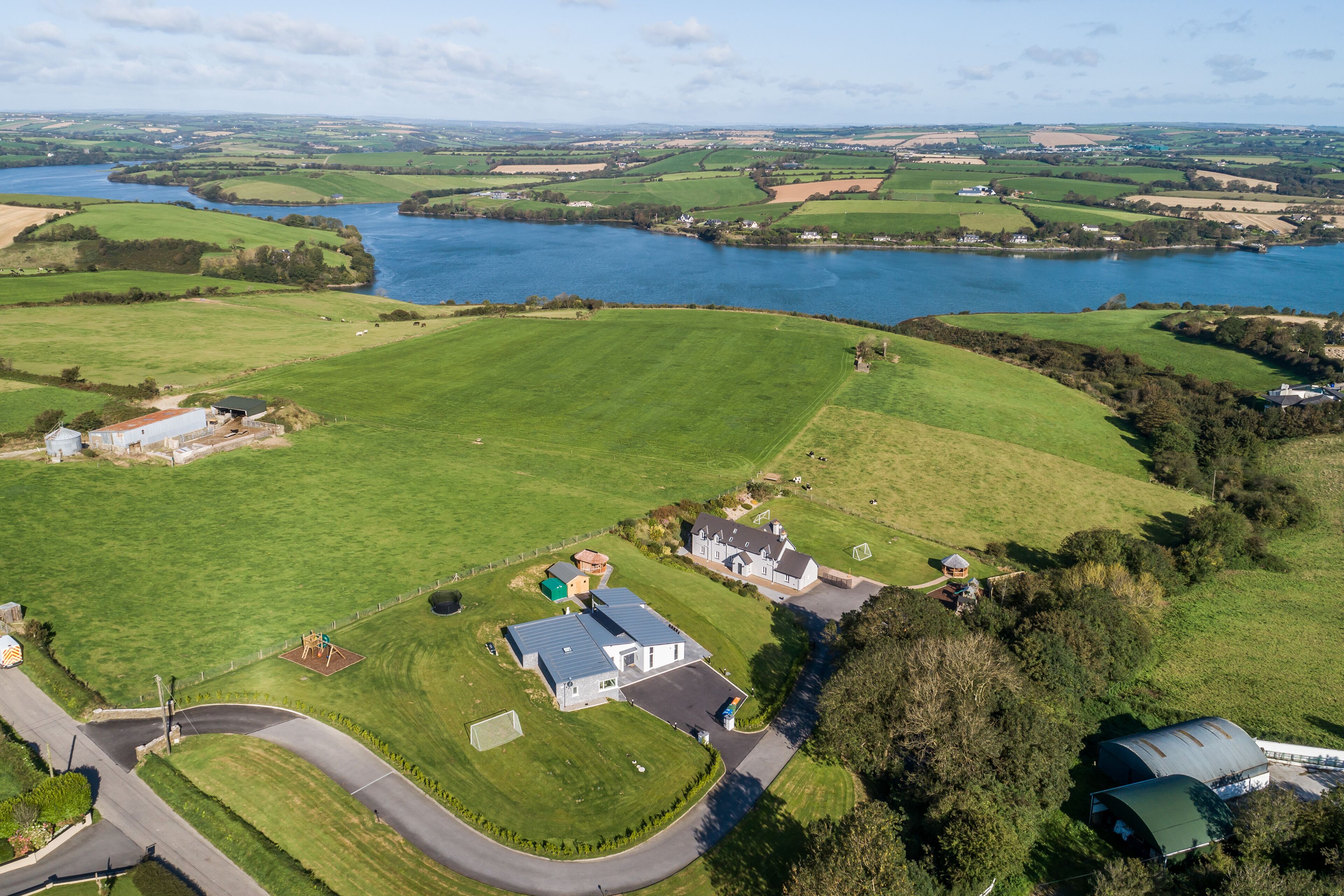 Vue aérienne d’une propriété rurale comprenant une grande maison, une grange et un lac.