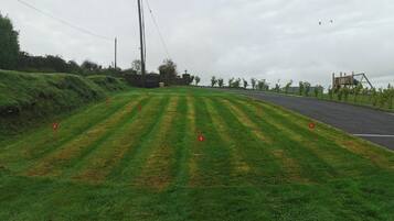 A grassy area with numbered markers, a road, and a playground structure.