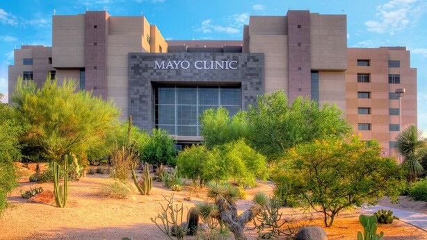 Un edificio de clínica con un cartel que dice "MAYO CLINIC" y rodeado de vegetación desértica.