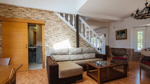 A spacious living area with a wooden floor, a sofa, a glass coffee table, and a staircase with white balusters. - Villa Los Naranjos, oasis with jacuzzi 15 minutes from Seville (Almensilla)