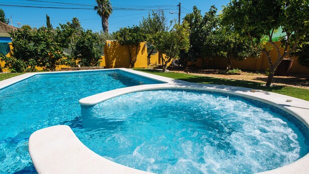A rectangular swimming pool with a hot tub area, surrounded by a yellow wall and greenery. - Villa Los Naranjos, oasis with jacuzzi 15 minutes from Seville (Almensilla)