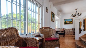 A spacious living room with wicker furniture, a dining area, and a staircase leading to an upper level. - Villa Los Naranjos, oasis with jacuzzi 15 minutes from Seville (Almensilla)