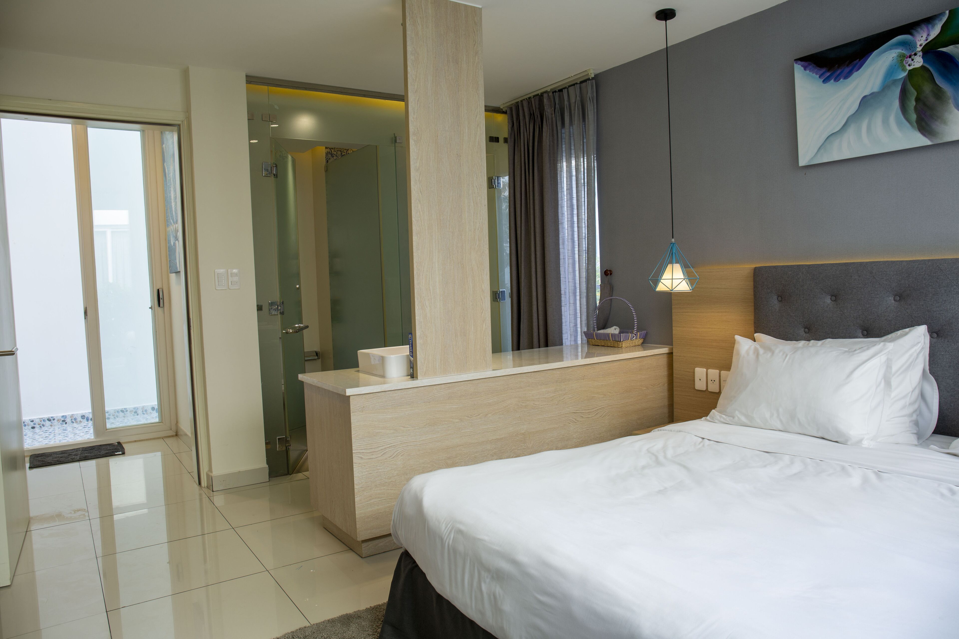 A modern hotel room with a bed, a desk, and a shower area.