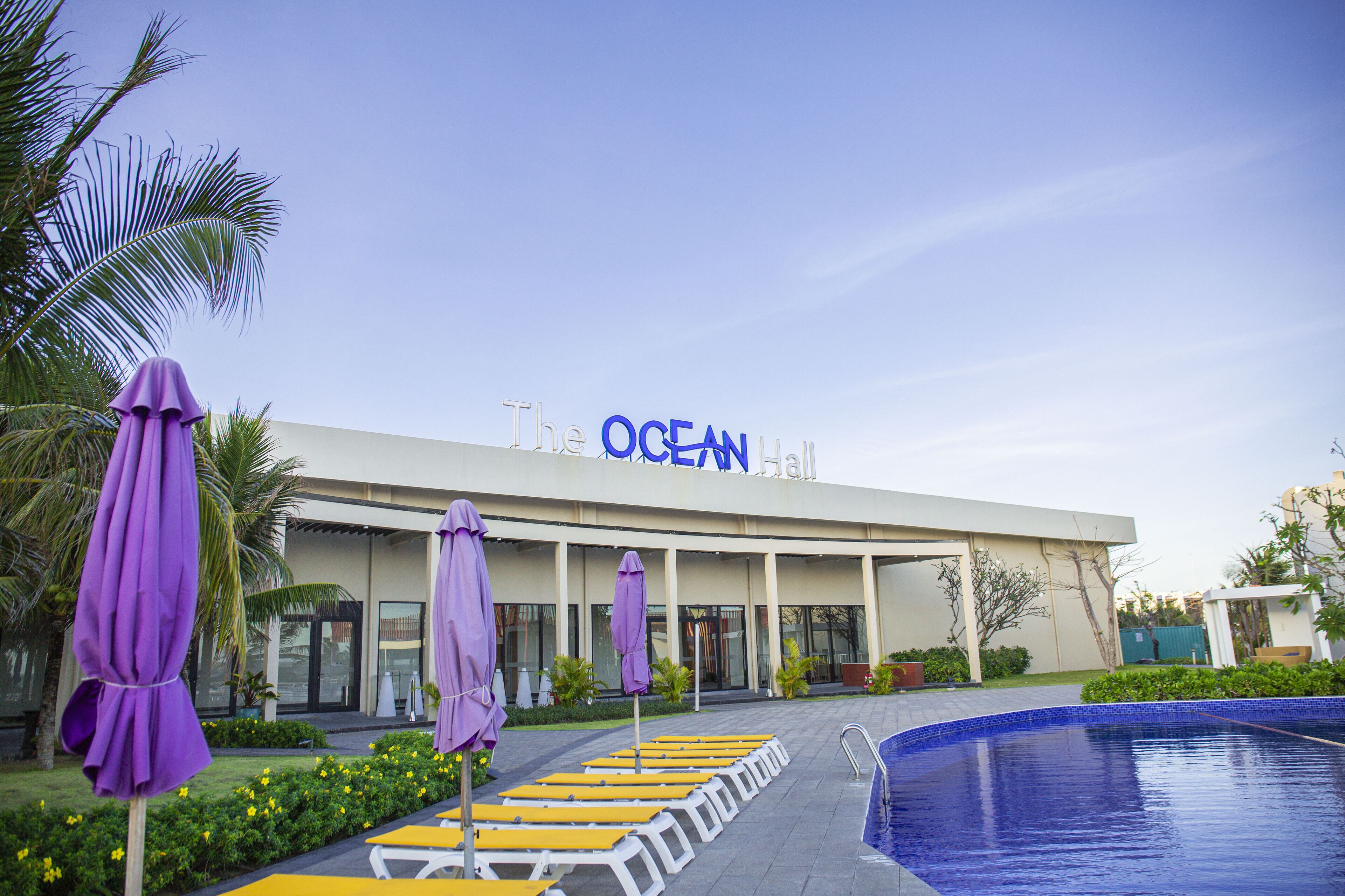 Die Ocean Hall mit Schwimmbad, violetten Sonnenschirmen und gelben Liegestühlen.