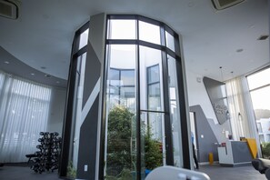 A modern office space with a glass corner wall, a reception desk, and a row of dumbbells.