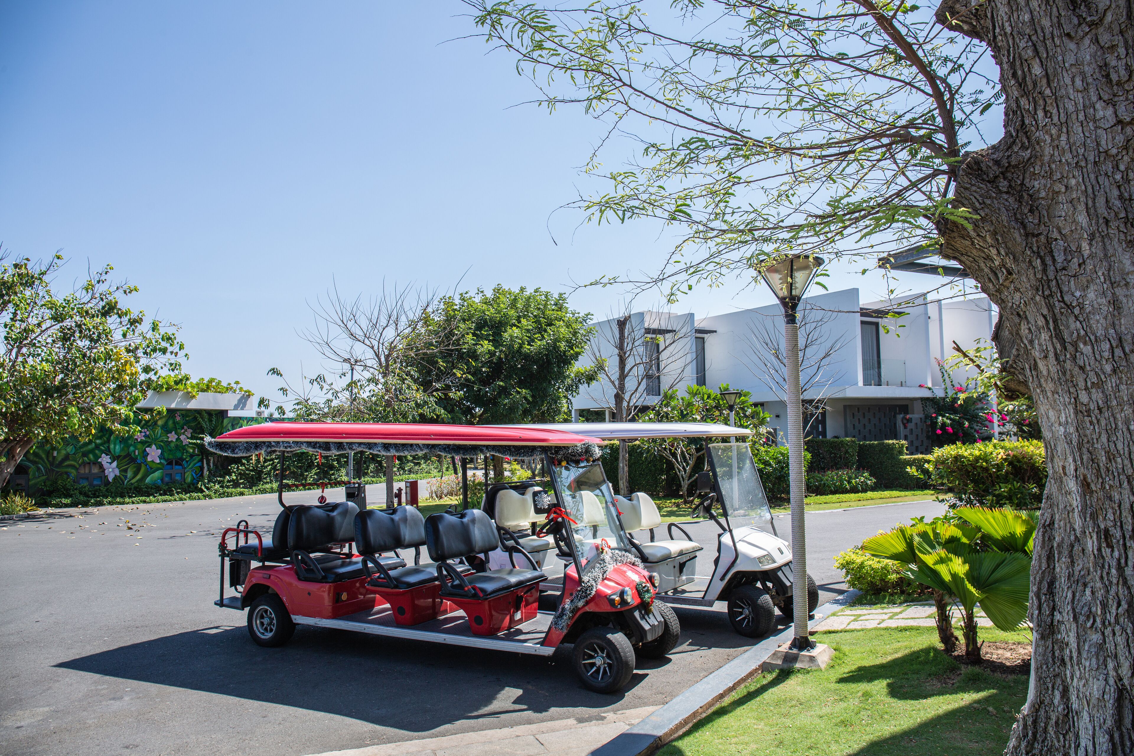 A red and white golf cart parked on a street with a clear sky.