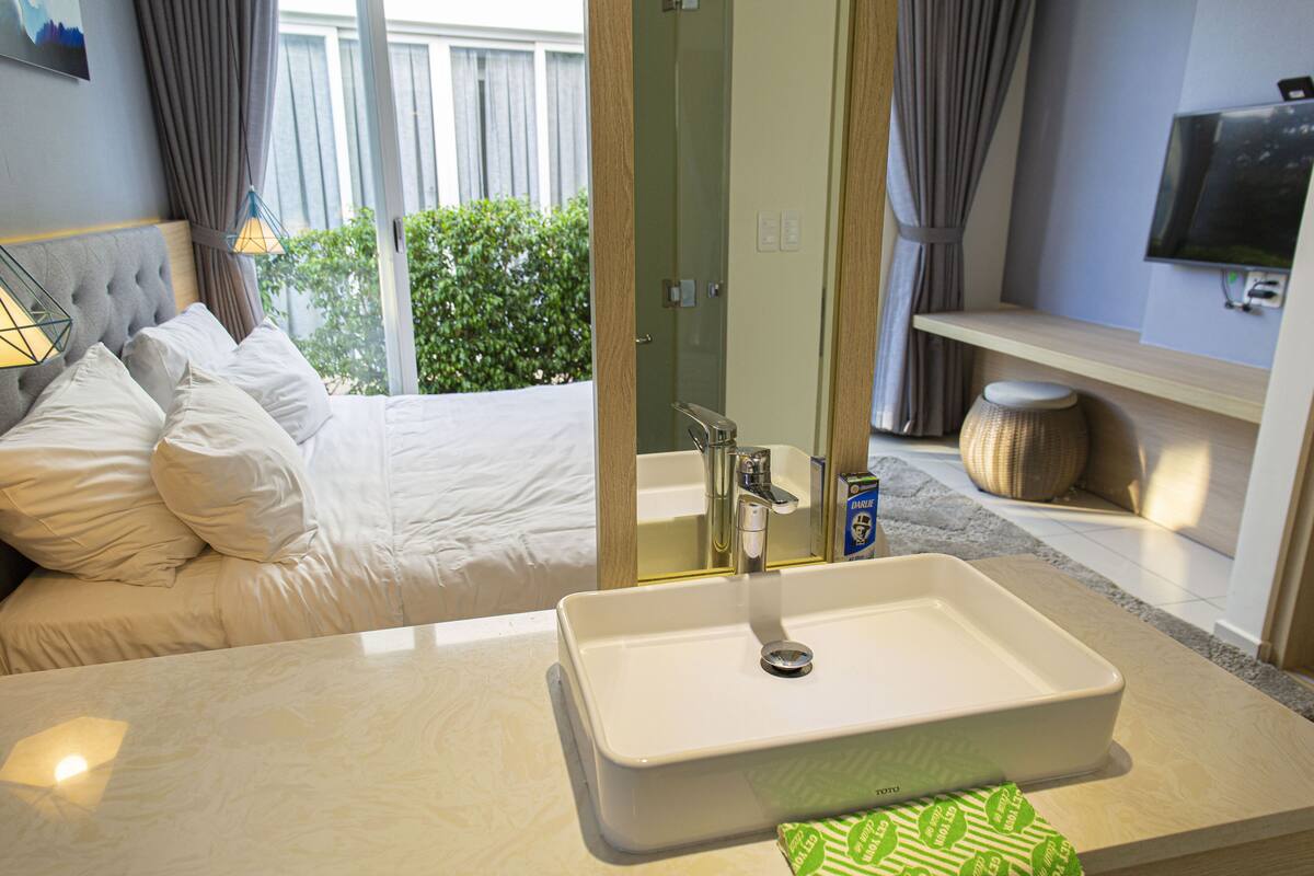 Une chambre d’hôtel avec un lit, une salle de bain avec un lavabo et un téléviseur fixé au mur.