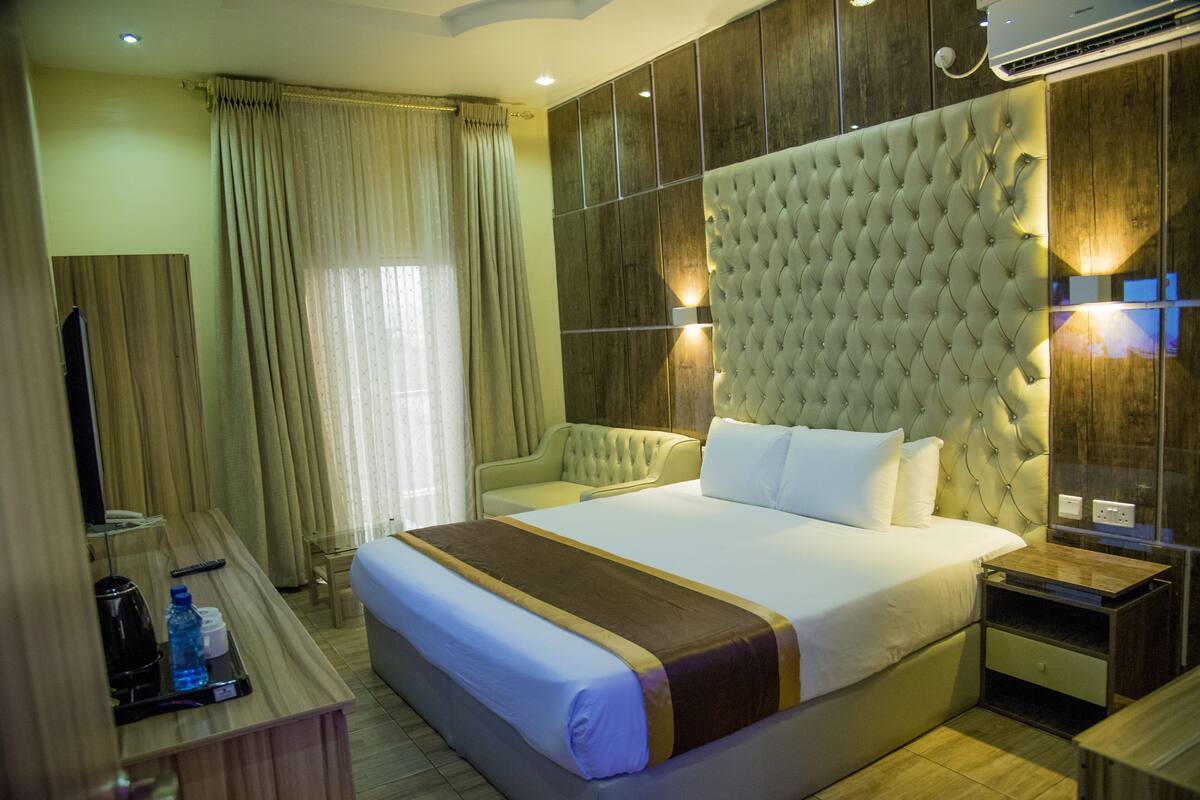A hotel room with a large bed, a bedside table, a TV, and a mirror.
