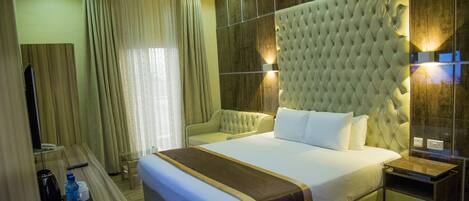 A hotel room with a large bed, a bedside table, a TV, and a mirror.