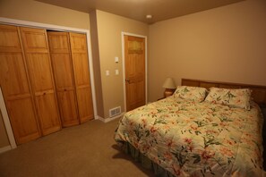 A bedroom with a bed, wooden closet, and a nightstand with a lamp. - Spacious 3-Unit Group Rental - Sleeps Large Groups (Polson)