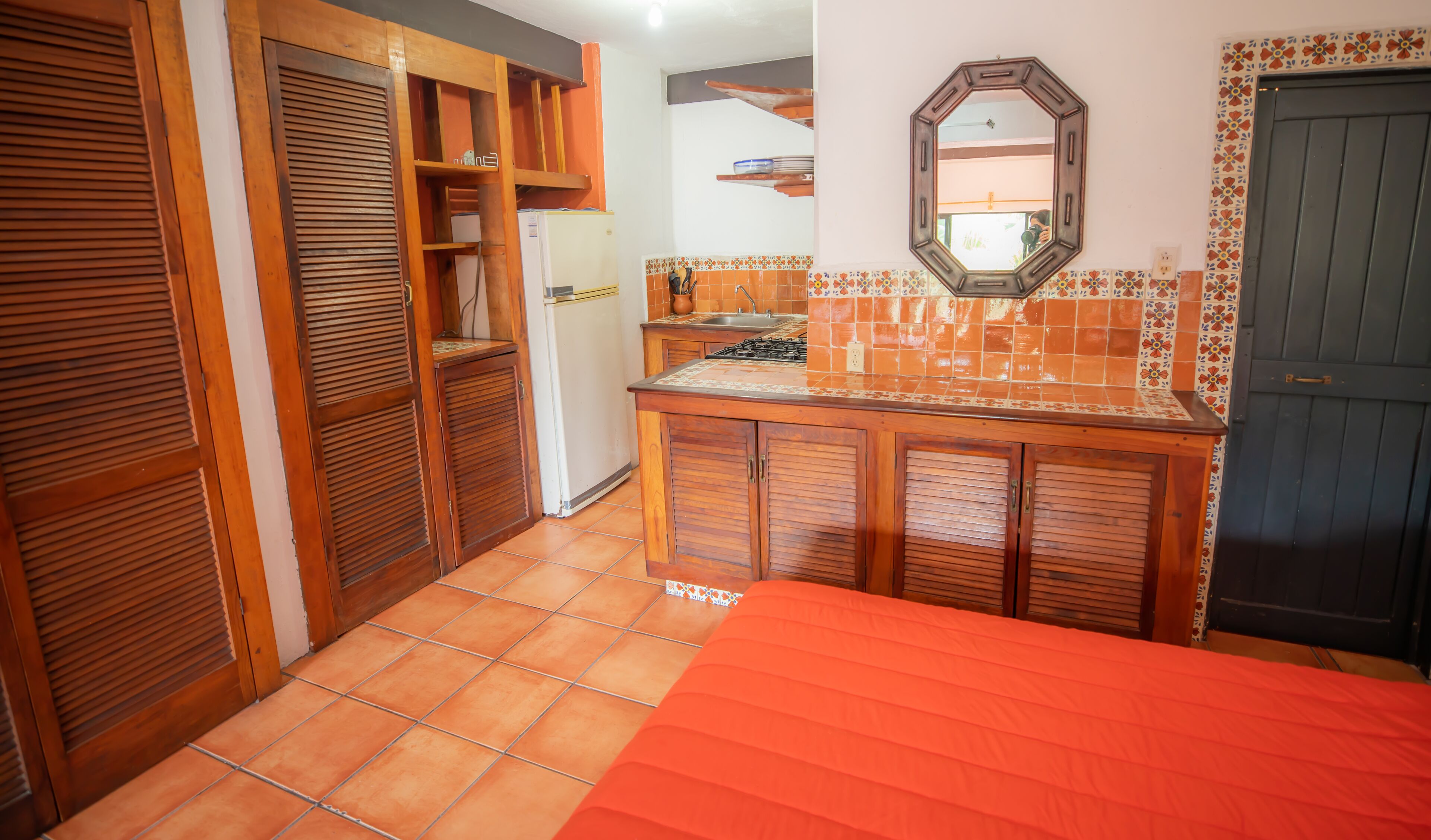 A compact kitchen with wooden cabinets, a tiled backsplash, and a small countertop.