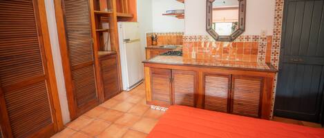 A compact kitchen with wooden cabinets, a tiled backsplash, and a small countertop.