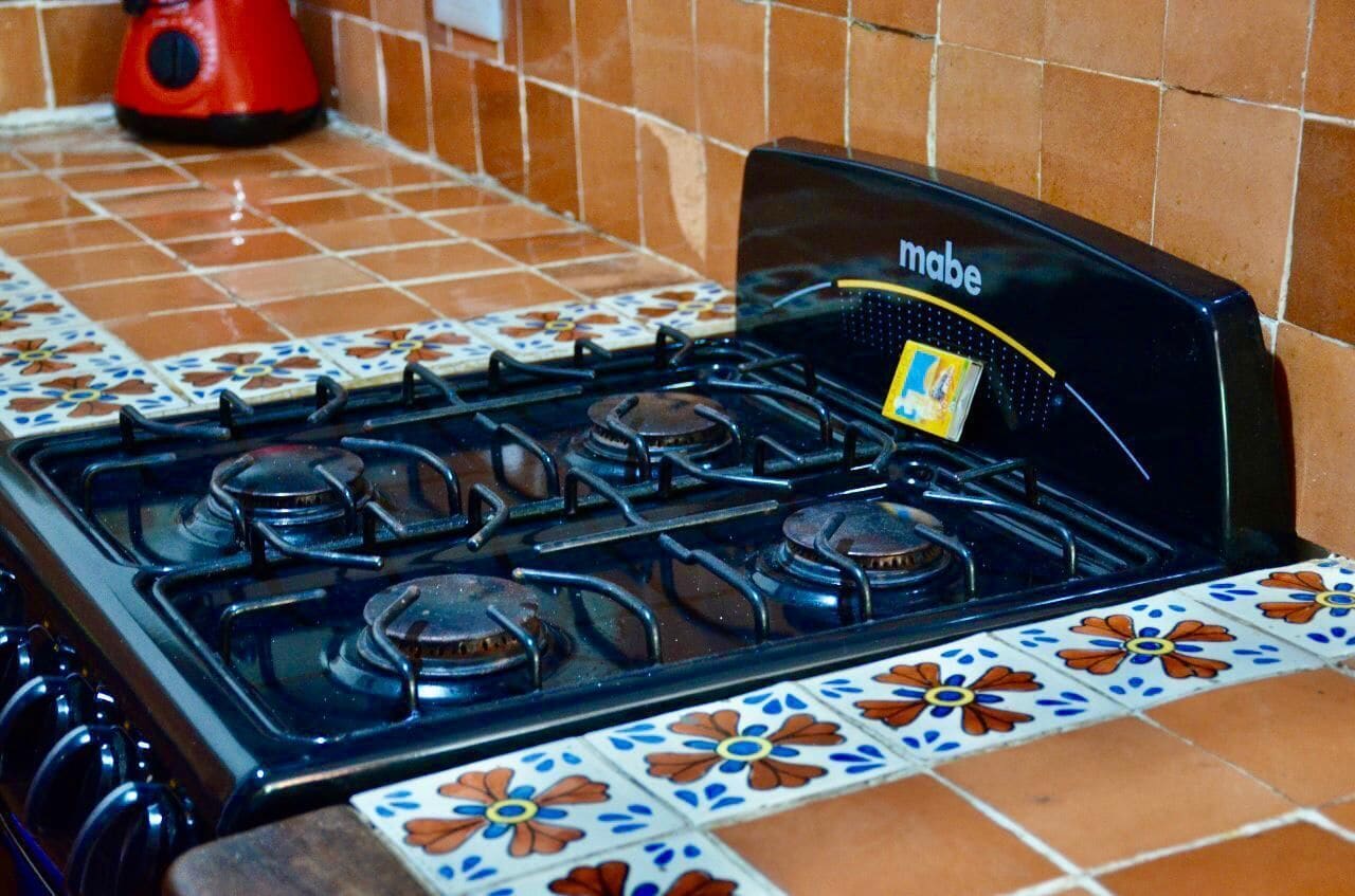 Une cuisinière noire dotée de quatre brûleurs et d’un panneau de commande portant l’inscription « Mabe ».
