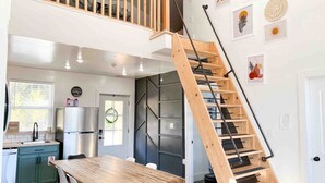 Une cuisine moderne avec une table à manger en bois, une cuisinière encastrée et un réfrigérateur en acier inoxydable.