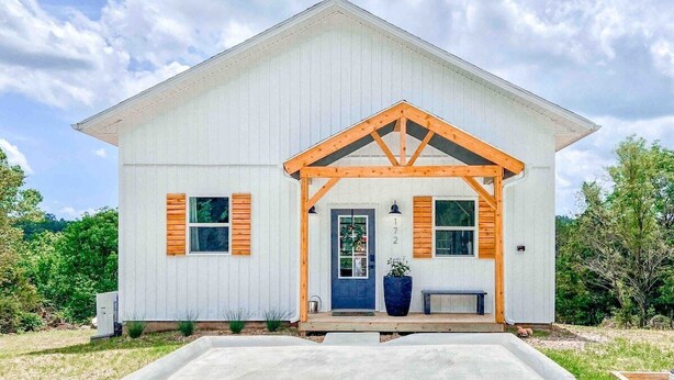 Un bâtiment blanc avec un porche en bois et une porte bleue.