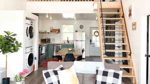 Un appartement compact comprenant un coin repas, une cuisine et un escalier en bois.