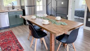 Une cuisine moderne avec une table à manger en bois, des chaises noires et un réfrigérateur en acier inoxydable.