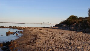 A beach with a rocky shoreline, a bridge in the background, and sparse vegetation. - Maxe house, Paula house - golf course, beach and surfing area within walking distance (Wulfen)