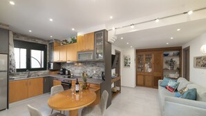 Una cocina moderna con armarios de madera, una mesa de comedor con sillas y una sala de estar con sofá y cojines decorativos.