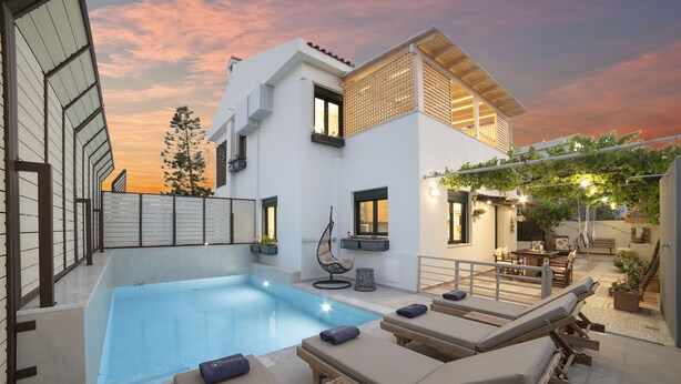 Una casa moderna con piscina, sillones de descanso y un área de patio.
