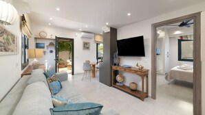 Una sala de estar moderna con sofá, televisor y comedor.