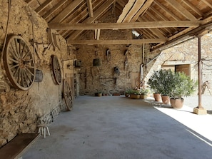 Ein rustikales Interieur mit Steinwänden, Holzbalken und großen Rädern.