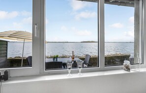 A view from a window overlooking a body of water, with a table and chairs outside. - Amazing home in Otterup with WiFi (Otterup)