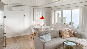 Una sala de estar acogedora con un sofá, una mesa de comedor y un ventanal con vistas.