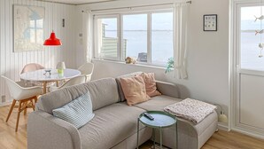 Una sala de estar acogedora con un sofá, una mesita y vista al mar.
