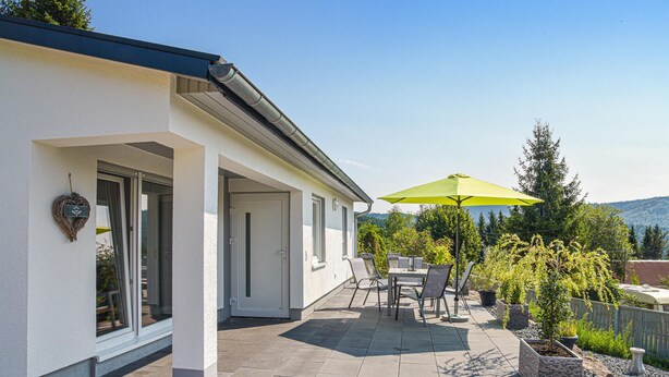A house with a patio, a green umbrella, and potted plants. - Cozy home in Goldlauter-Heidersbach (Goldlauter-Heidersbach)