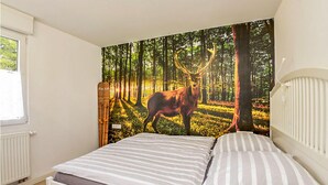 A bedroom with a bed, a window, and a forest-themed wall mural. - Cozy home in Goldlauter-Heidersbach (Goldlauter-Heidersbach)