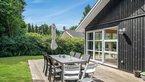 An outdoor patio with a wooden deck, a table with chairs, and a large umbrella. - Beautiful home in Rønne with WiFi (Rønne)