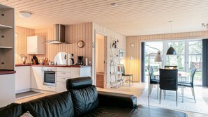 A modern kitchen with wooden paneling, a dining area with a table and chairs, and a leather sofa in a living room. - Beautiful home in Rønne with WiFi (Rønne)