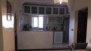 Een keuken met een centraal eiland, een eethoek met een tafel en een bank.