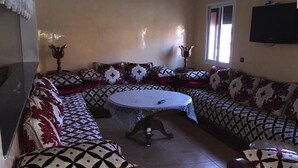 Een woonkamer met een zithoek, een rond bijzettafeltje en twee decoratieve vazen.