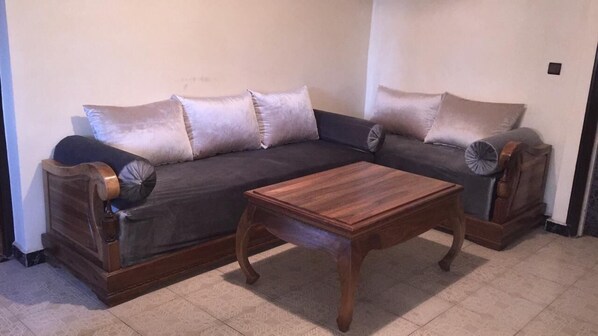 A living room with a dark-colored sofa set, a wooden coffee table, and a patterned rug.