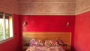 Een kamer met een bed, rode wanden en een behang met patroon.